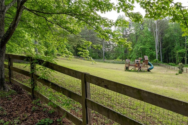view of yard featuring a playground and a wooded view