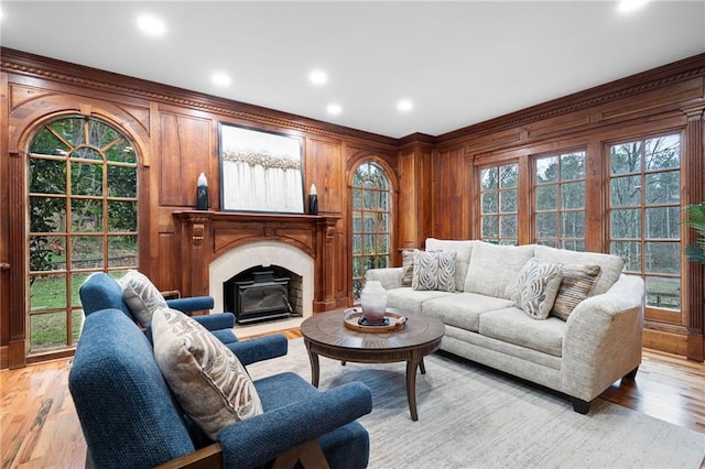 living area with healthy amount of natural light, light wood finished floors, a fireplace, wood walls, and recessed lighting