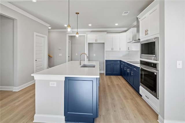 kitchen featuring sink, blue cabinetry, appliances with stainless steel finishes, a kitchen island with sink, and decorative light fixtures