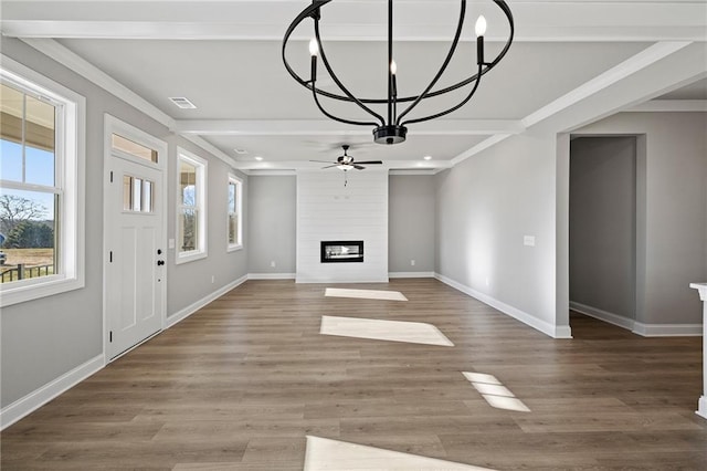 unfurnished living room with ornamental molding, ceiling fan with notable chandelier, hardwood / wood-style floors, and a fireplace