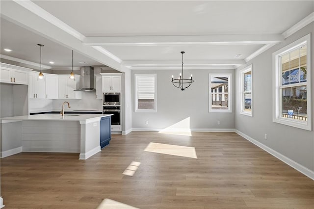 kitchen with hanging light fixtures, appliances with stainless steel finishes, white cabinets, and wall chimney exhaust hood