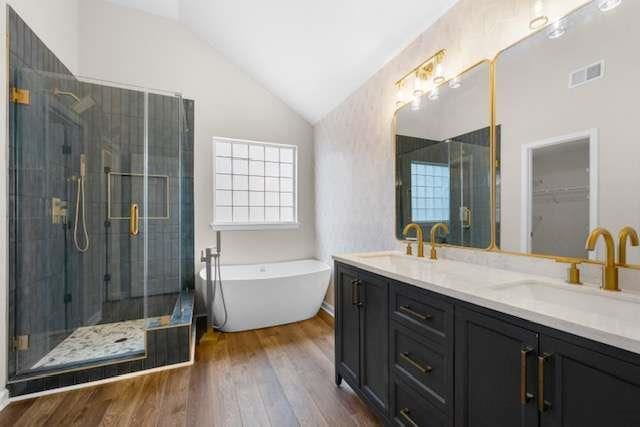 bathroom featuring hardwood / wood-style flooring, vanity, plus walk in shower, and vaulted ceiling