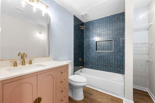 full bathroom with vanity, hardwood / wood-style flooring, tiled shower / bath combo, and toilet