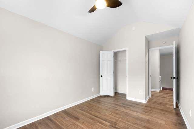 unfurnished bedroom with dark wood-type flooring, ceiling fan, vaulted ceiling, and a closet