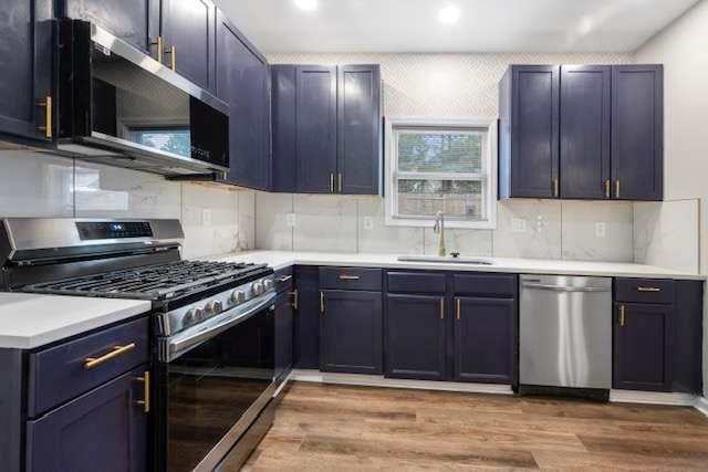 kitchen with stainless steel appliances, tasteful backsplash, sink, and light hardwood / wood-style flooring