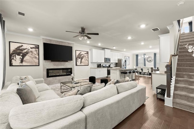 2227 Foley Park St, Snellville, GA 30078 - living room featuring stairs, crown molding, recessed lighting, a tiled fireplace, and ceiling fan