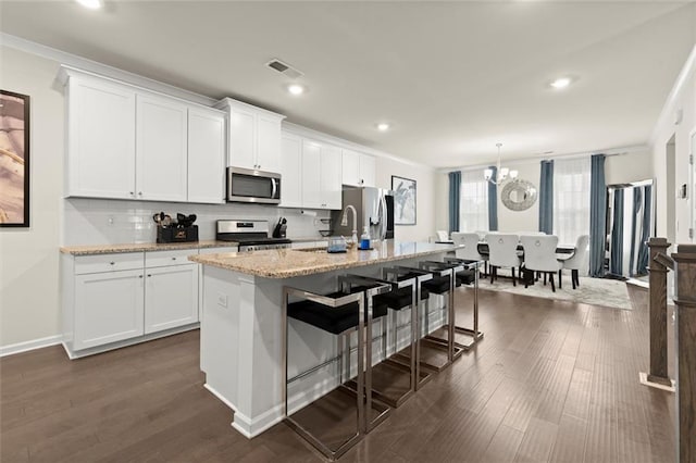 2227 Foley Park St, Snellville, GA 30078 - kitchen with appliances with stainless steel finishes, decorative backsplash, a breakfast bar area, an island with sink, and white cabinets