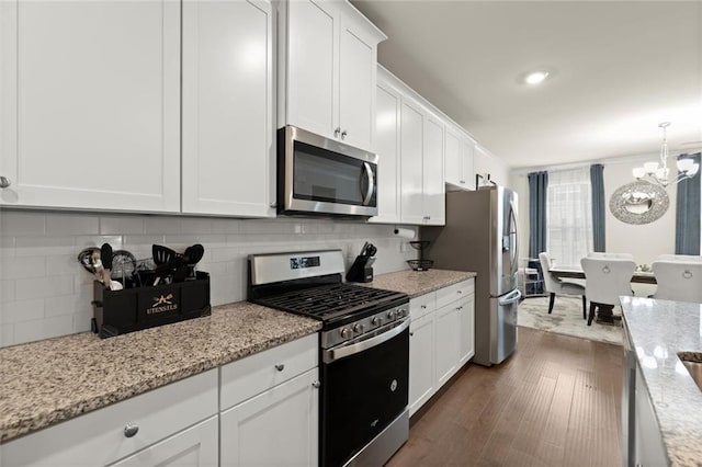 2227 Foley Park St, Snellville, GA 30078 - kitchen with stainless steel appliances, white cabinets, a chandelier, dark wood-type flooring, and decorative backsplash
