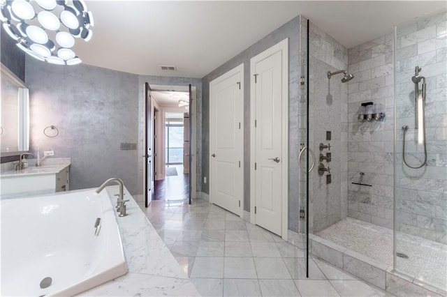 full bathroom with tiled shower, a freestanding bath, vanity, and marble finish flooring