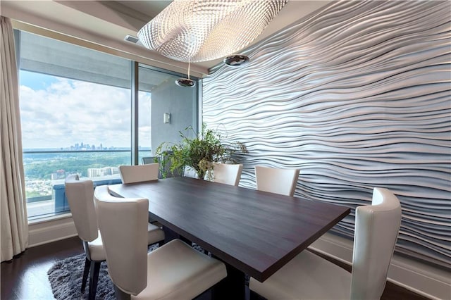 dining area featuring dark wood-style floors, a city view, and a chandelier