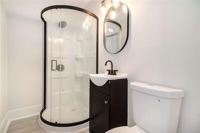 bathroom featuring toilet, wood-type flooring, vanity, and a shower with shower door