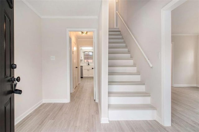 stairway featuring hardwood / wood-style flooring, crown molding, and sink