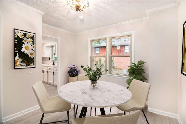 dining room featuring sink, crown molding, and light hardwood / wood-style flooring