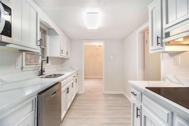 kitchen featuring appliances with stainless steel finishes, sink, light wood-type flooring, white cabinets, and a textured ceiling