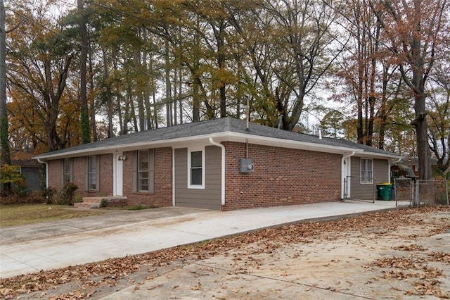 ranch-style home with brick siding, concrete driveway, and fence