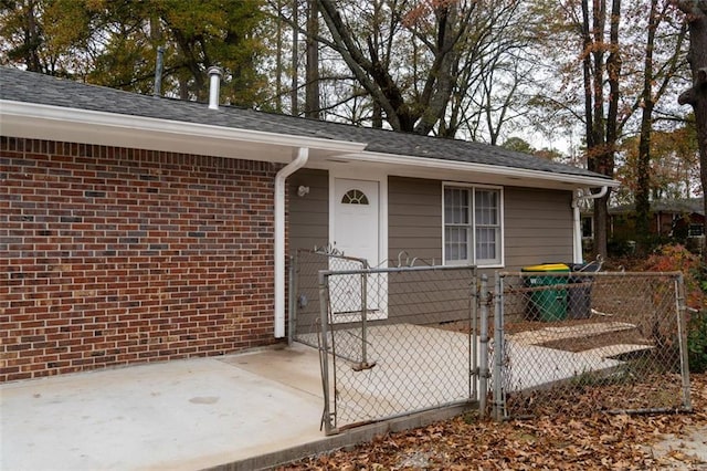 property entrance featuring brick siding, fence, and a gate