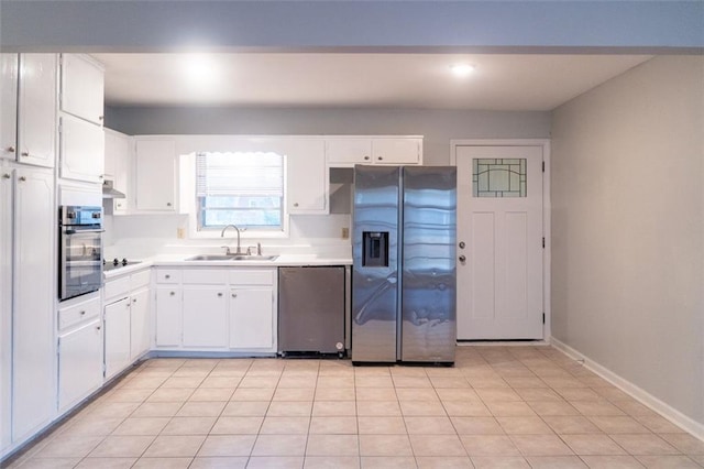 kitchen featuring baseboards, a sink, light countertops, appliances with stainless steel finishes, and white cabinetry