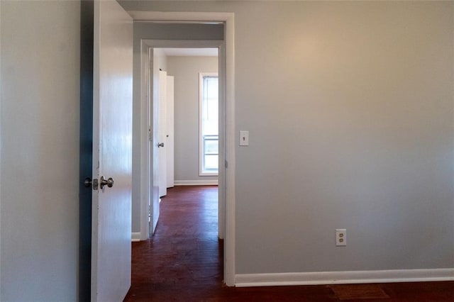 hall featuring dark wood-type flooring and baseboards