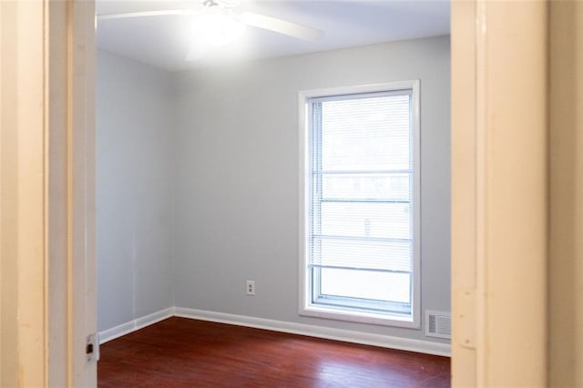 unfurnished room with dark wood finished floors, baseboards, visible vents, and ceiling fan