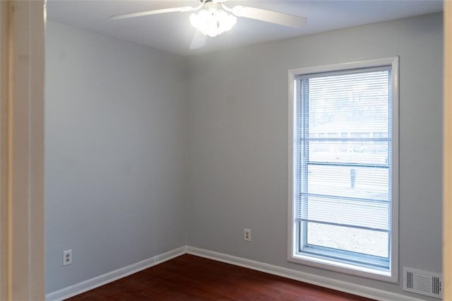 unfurnished room featuring dark wood-style floors, baseboards, visible vents, and ceiling fan