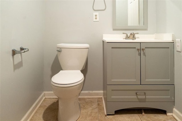 half bath featuring vanity, tile patterned floors, toilet, and baseboards