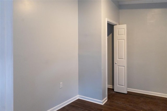 unfurnished room with baseboards and dark wood-style floors