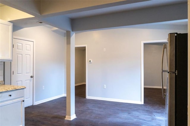 interior space featuring baseboards, light stone counters, freestanding refrigerator, dark wood-style floors, and white cabinetry