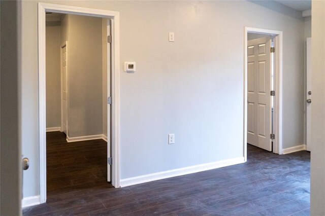 unfurnished room featuring baseboards and dark wood-type flooring