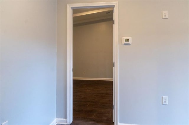 hallway featuring baseboards and dark wood-type flooring