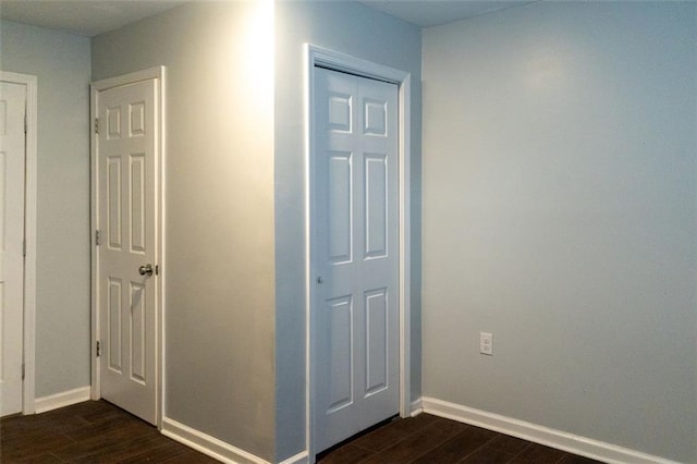 hallway with dark wood-type flooring and baseboards