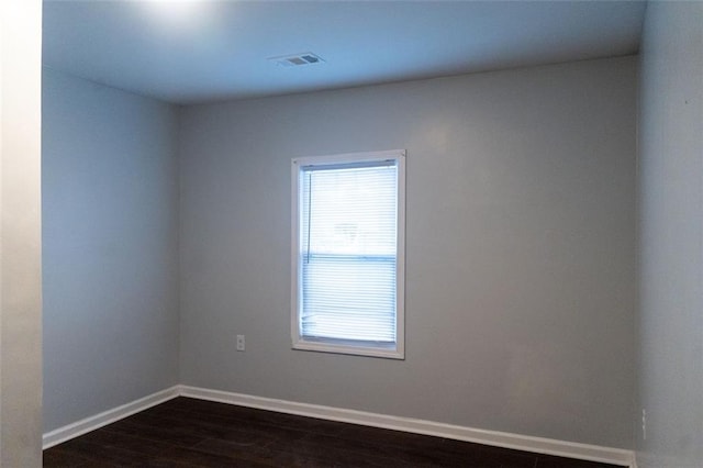 spare room featuring visible vents, dark wood-type flooring, and baseboards