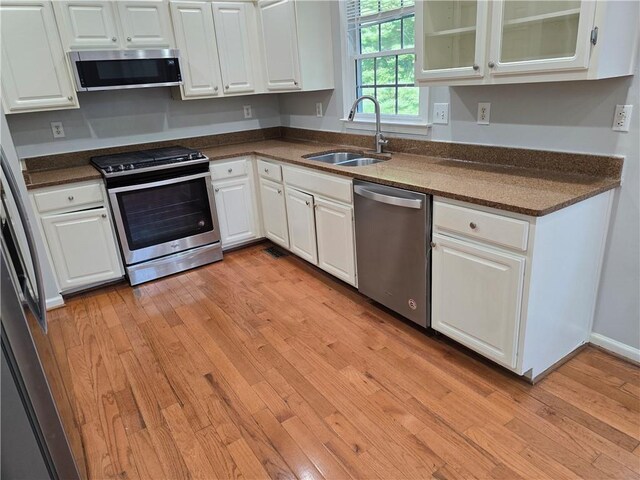 3773 Summer Rose Dr, Atlanta, GA 30341 - kitchen with appliances with stainless steel finishes, a sink, dark countertops, white cabinetry, and light wood-style floors