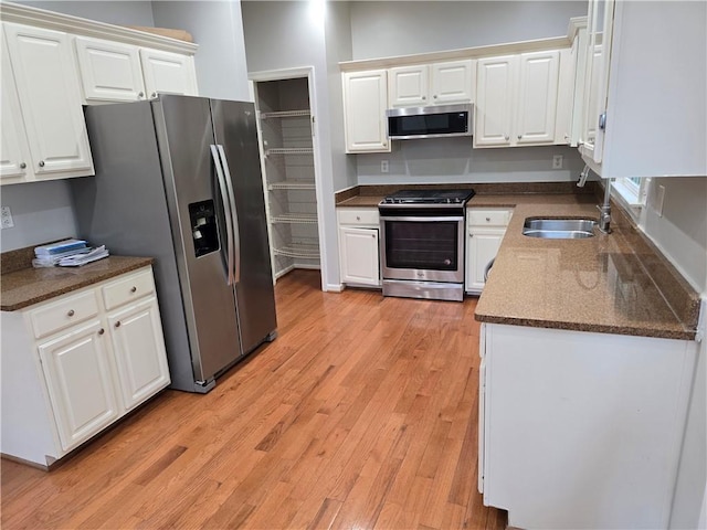 3773 Summer Rose Dr, Atlanta, GA 30341 - kitchen with stainless steel appliances, a sink, white cabinetry, light wood-type flooring, and dark stone counters