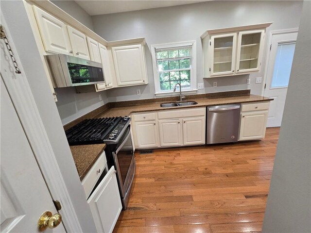 3773 Summer Rose Dr, Atlanta, GA 30341 - kitchen featuring stainless steel appliances, a sink, dark countertops, light wood-type flooring, and glass insert cabinets