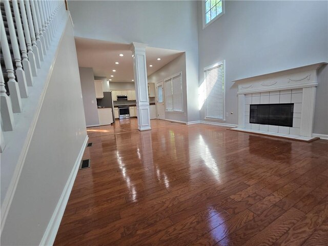 3773 Summer Rose Dr, Atlanta, GA 30341 - unfurnished living room with a tile fireplace, ornate columns, hardwood / wood-style floors, a towering ceiling, and baseboards