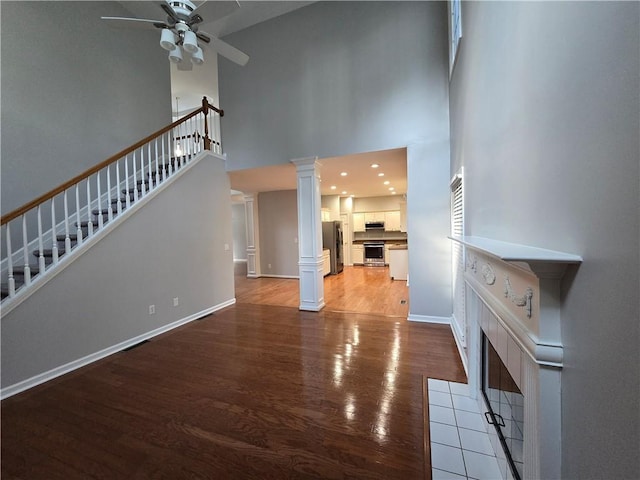 3773 Summer Rose Dr, Atlanta, GA 30341 - unfurnished living room featuring light wood-style flooring, ceiling fan, a tile fireplace, a high ceiling, and stairs