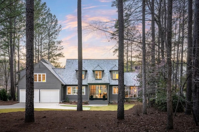 back of house at dusk featuring concrete driveway and a garage