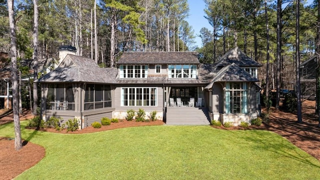 back of house with a lawn, a chimney, and a sunroom