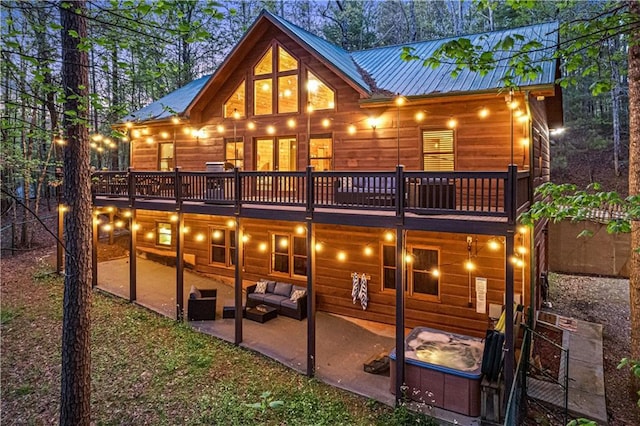 rear view of house featuring a deck, an outdoor living space, a patio area, and metal roof