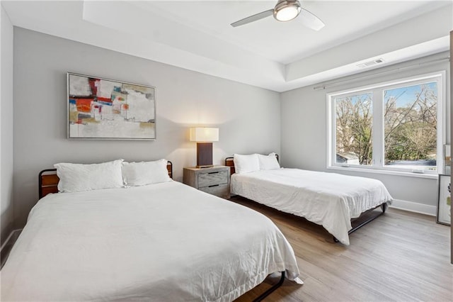 bedroom featuring hardwood / wood-style flooring, a raised ceiling, and ceiling fan