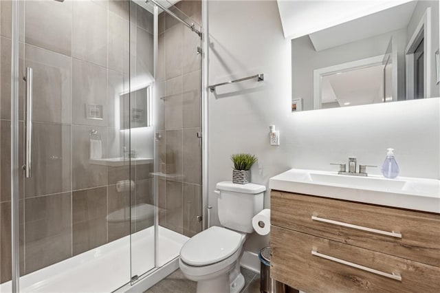 bathroom featuring vanity, a shower with door, and toilet