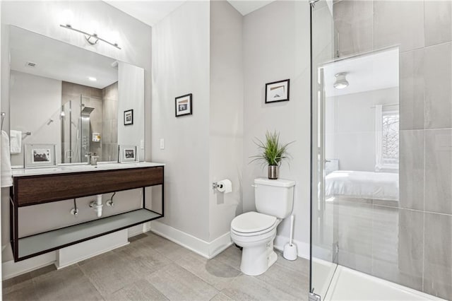 bathroom featuring tile patterned flooring, vanity, a tile shower, and toilet