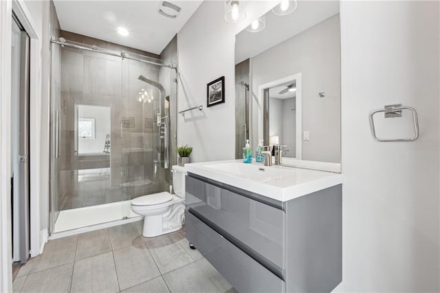 bathroom with vanity, ceiling fan, toilet, a shower with door, and tile patterned floors