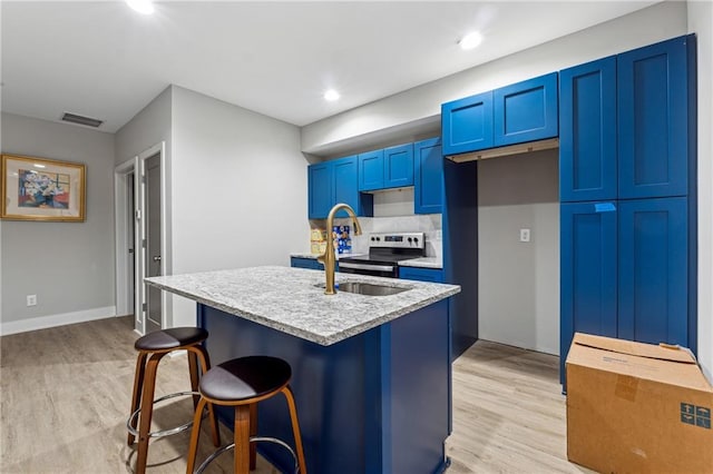 kitchen featuring blue cabinetry, a kitchen bar, sink, stainless steel range with electric cooktop, and a kitchen island with sink