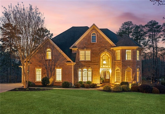 view of front of house with french doors, brick siding, and a front yard