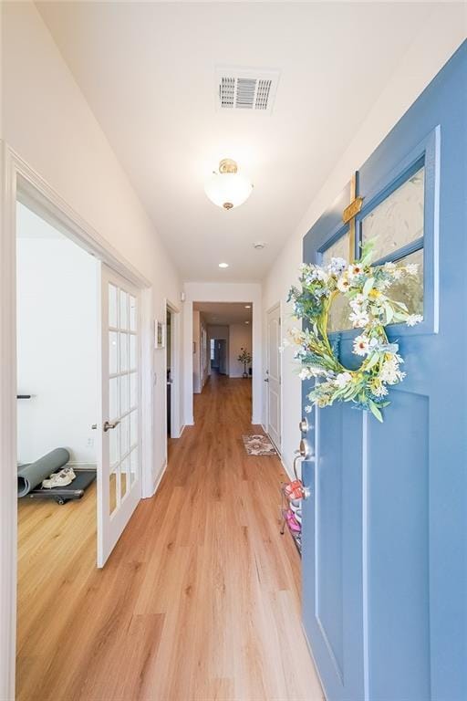 corridor featuring visible vents, french doors, and light wood finished floors