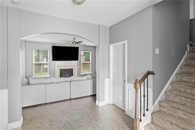 133 Worthing Ln, Fairburn, GA 30213 - living area featuring ceiling fan, arched walkways, a glass covered fireplace, stairs, and tile patterned floors