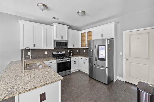 133 Worthing Ln, Fairburn, GA 30213 - kitchen featuring appliances with stainless steel finishes, a peninsula, tasteful backsplash, light stone counters, and white cabinets