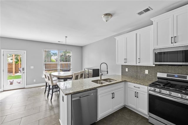 133 Worthing Ln, Fairburn, GA 30213 - kitchen featuring appliances with stainless steel finishes, a peninsula, white cabinetry, backsplash, and light stone counters