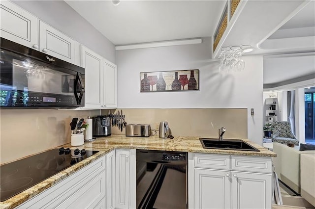 kitchen featuring black appliances, white cabinetry, light stone countertops, and sink